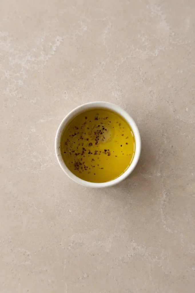 Olive oil dressing with black pepper in a small bowl for cantaloupe salad