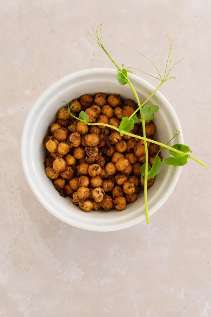 crispy chickpeas cooked in air fryer in a white bowl with fresh microgreens, photographed in natural light