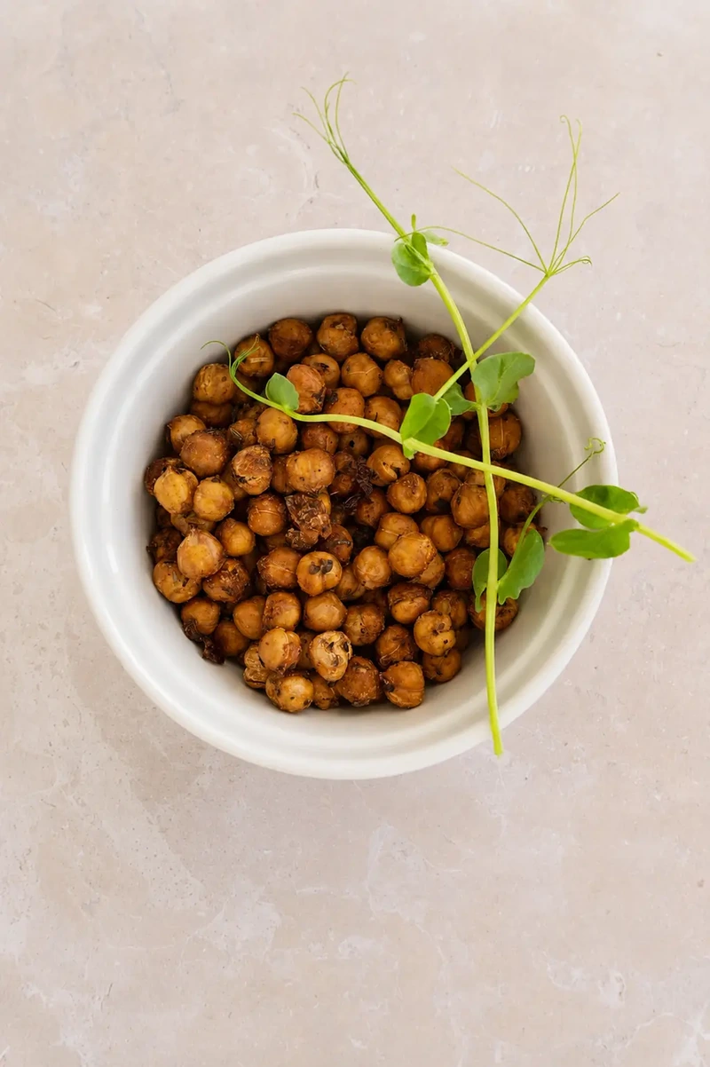 crispy chickpeas cooked in air fryer in a white bowl with fresh microgreens, photographed in natural light