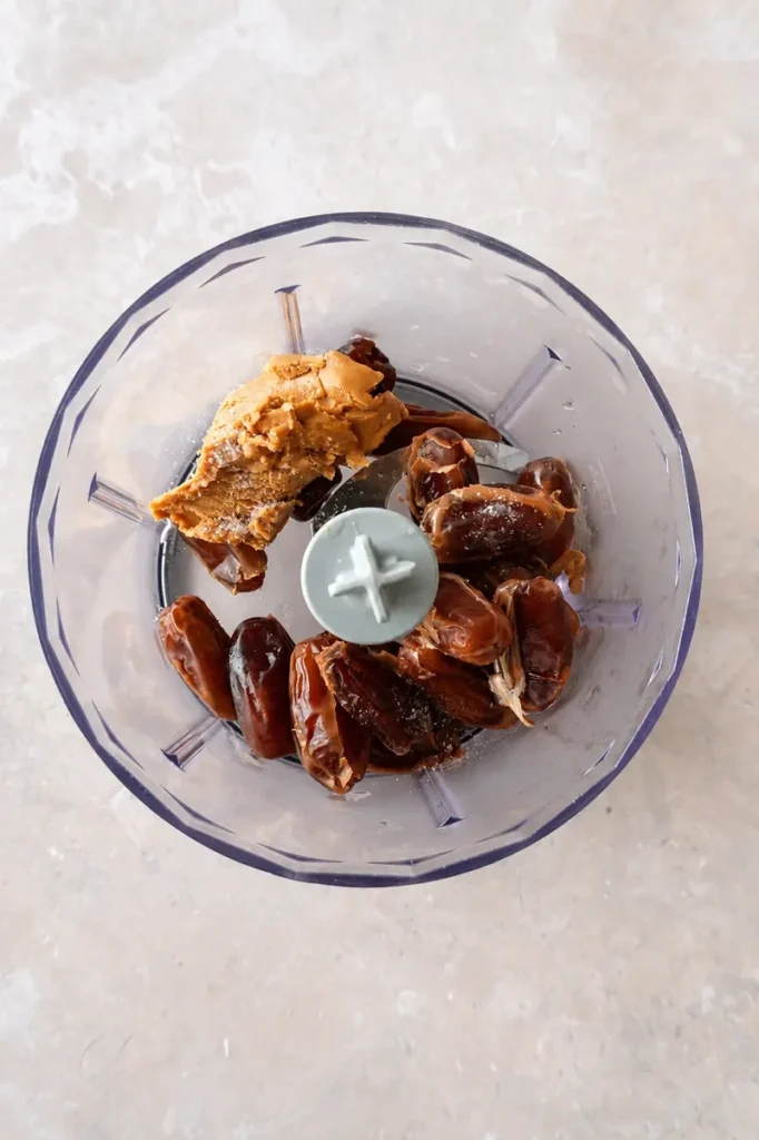 Medjool date caramel sauce ingredients in a blender with dates, peanut butter, and a pinch of salt before blending.