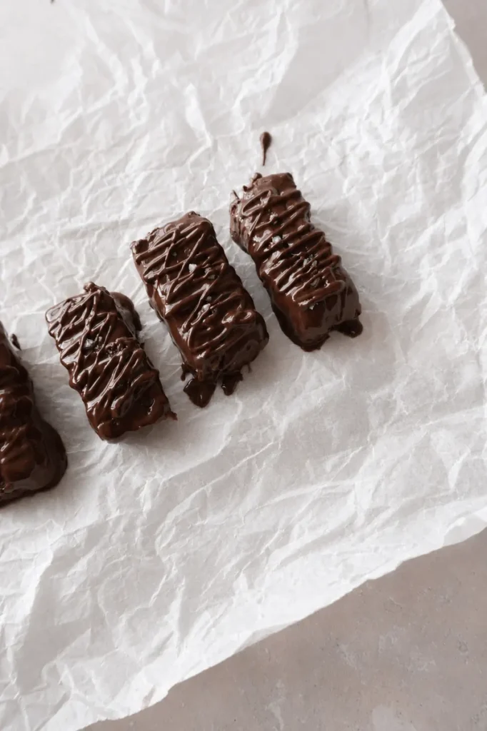 Easy Vegan Twix Bars with Dates chocolate-covered bars on parchment paper with a glossy drizzle and soft natural light.