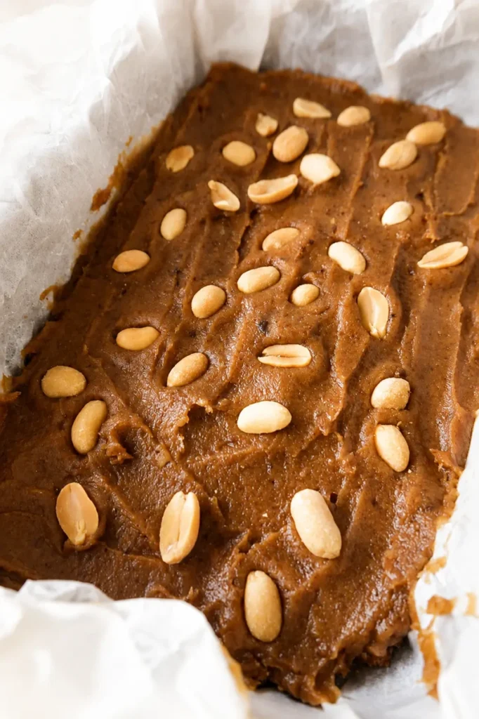 Easy Vegan Twix Bars with Dates topped with peanuts before adding the chocolate coating.