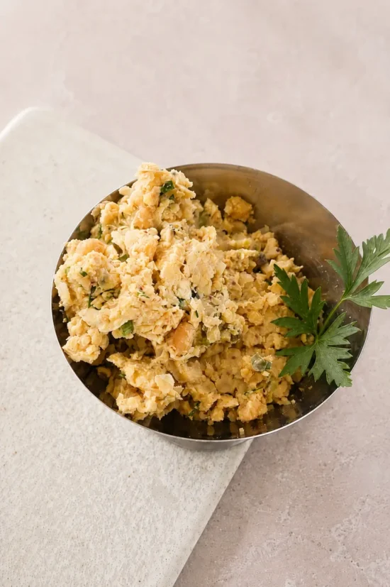 Vegan chickpea tuna salad served in a small metal bowl with fresh parsley garnish.