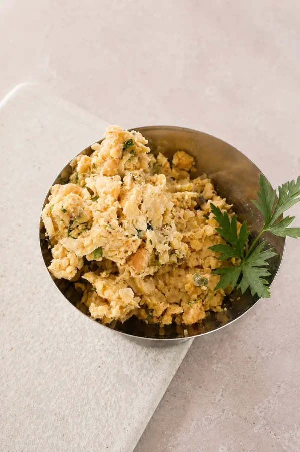 Vegan chickpea tuna salad served in a small metal bowl with fresh parsley garnish.
