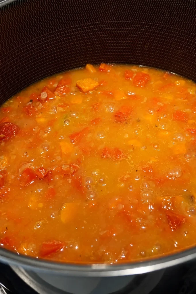 Pumpkin and red lentil soup simmering in a pot until creamy and soft.