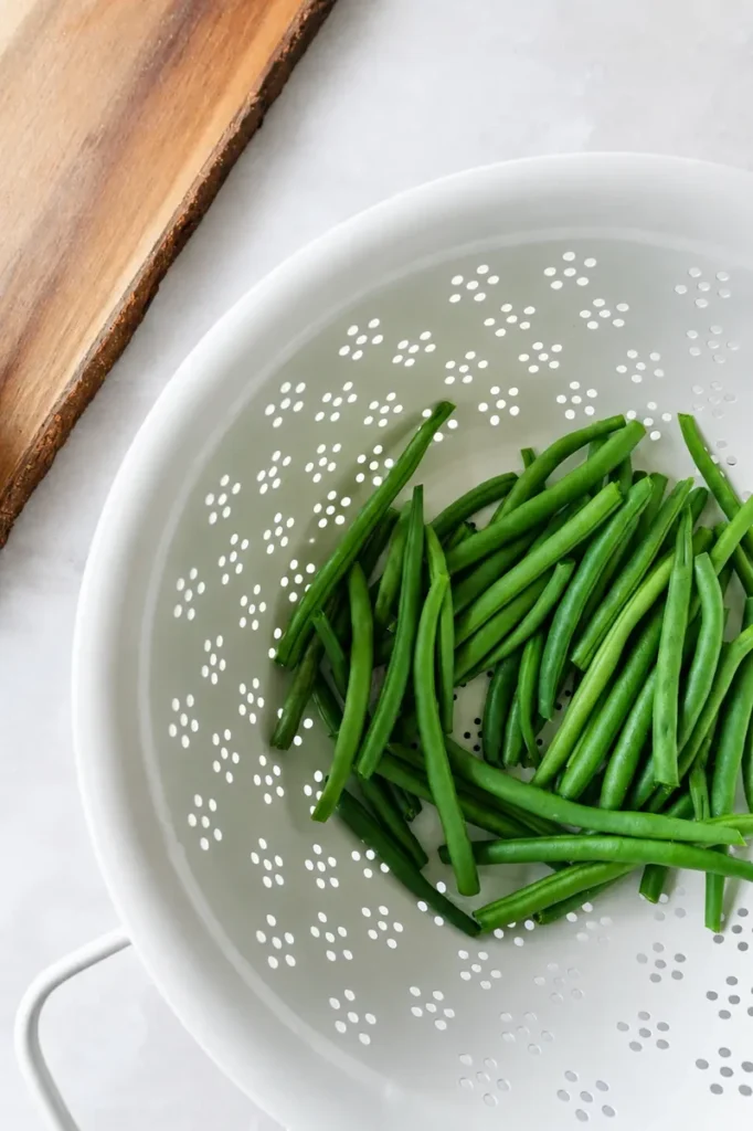 Roasted green beans recipe preparation with fresh green beans rinsed in a colander before trimming and seasoning.