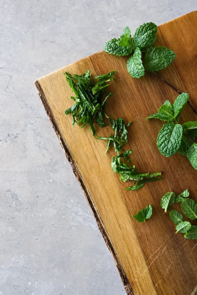 Zucchini recipe prep with chopped fresh mint on a rustic wooden board, photographed in cool natural light.