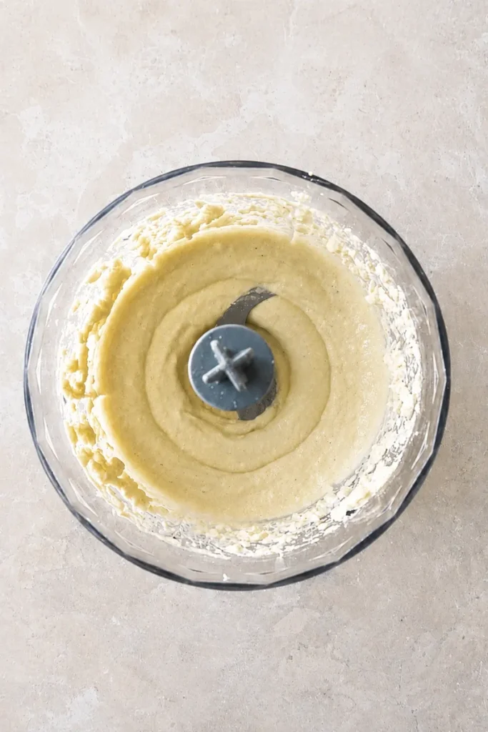 Vegan aioli blended into a smooth creamy sauce inside a food processor bowl.