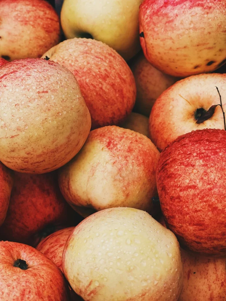 Vegan apple cake red apples photographed on a light stone surface, ready to be sliced and used in the recipe.