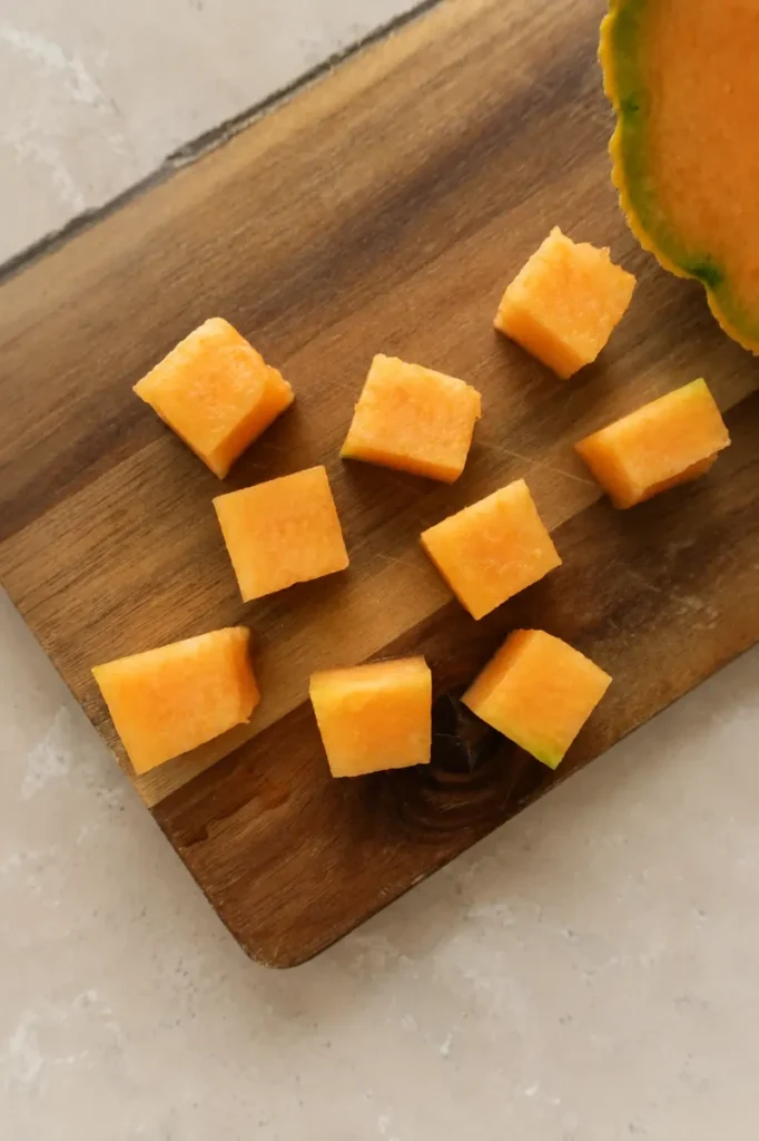 Fresh cantaloupe cubes on a wooden board for cantaloupe salad