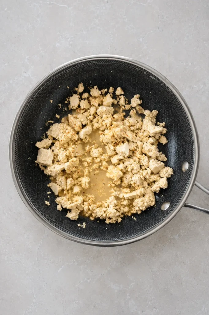 vegan tofu scramble close-up of seasoned tofu pieces cooking in a nonstick pan