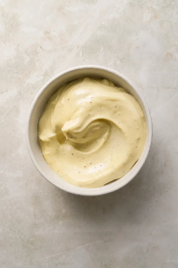 Vegan mayo in a small bowl with a smooth, creamy texture and soft overhead light.