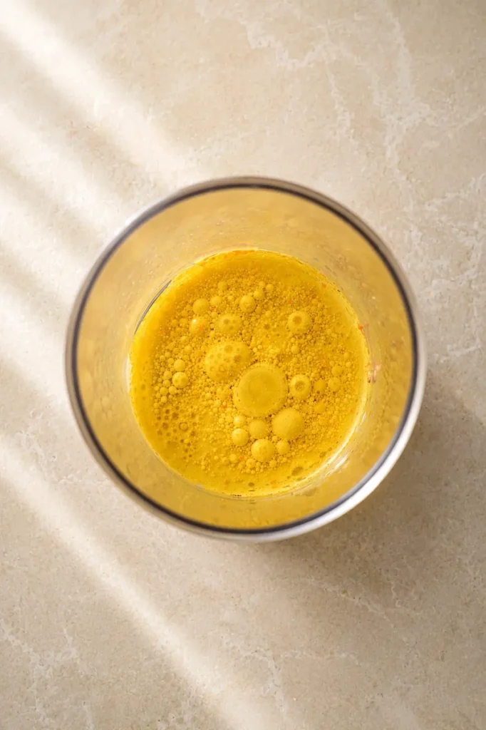 Vegan mayo mixture with oil and spices in a blender cup, ready to be emulsified.