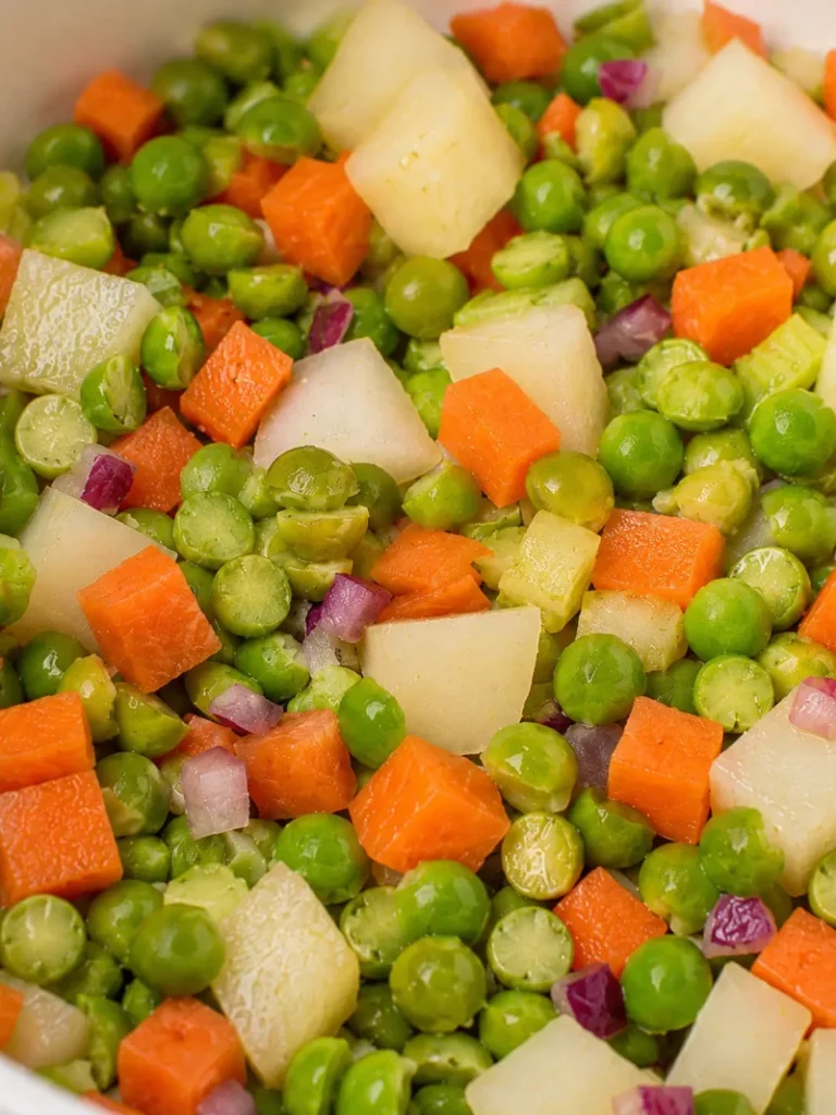 Split pea soup recipe close-up with green split peas, diced potatoes, carrots, celery, and red onion during cooking.