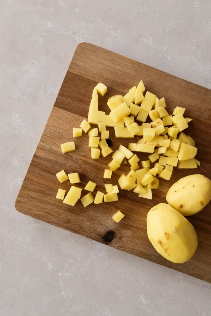 Vegan potato leek soup prep with diced potatoes and sliced leeks in a large pot.