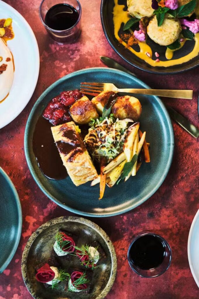 Mildreds London table with vibrant vegan fusion dishes, fresh vegetables, dips, and colourful plant-based plates in a top view.