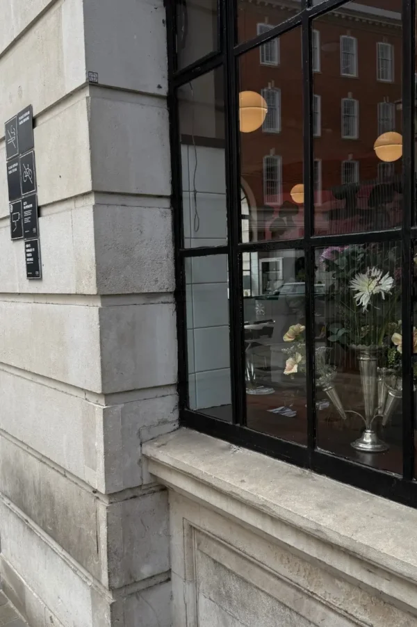London street view with a charming restaurant window decorated with flowers, creating a cozy vegan travel guide atmosphere.