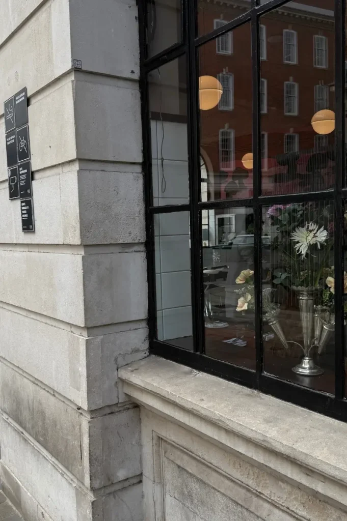London street view with a charming restaurant window decorated with flowers, creating a cozy vegan travel guide atmosphere.