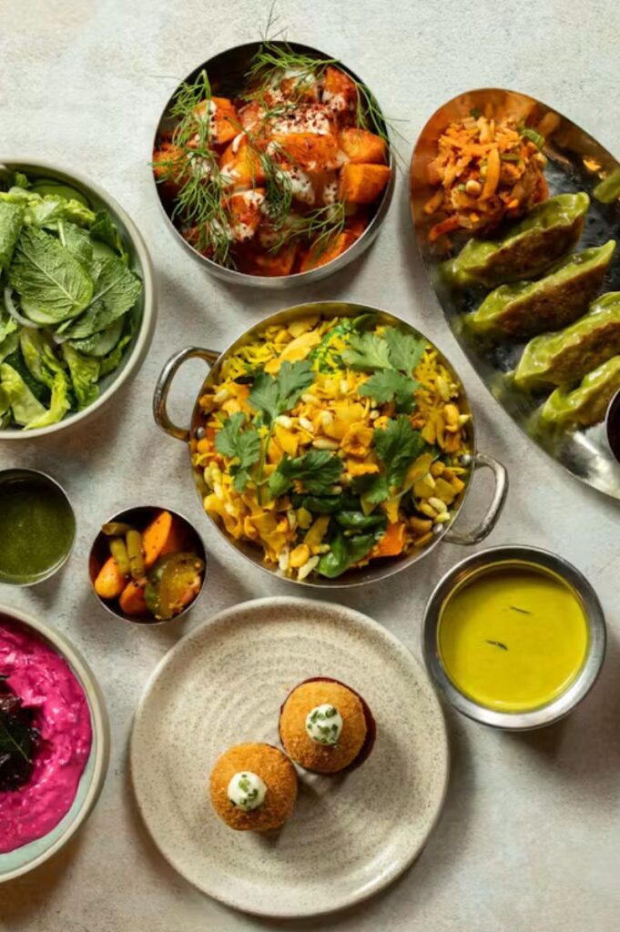 Mildreds Soho vegan dinner spread with colourful fusion dishes, hummus, salad, vegetables, and plant-based plates seen from above.