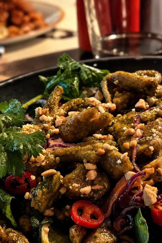 Busaba vegan salad with fresh herbs, red chili, crushed peanuts, and green-coated bites served in a black bowl.