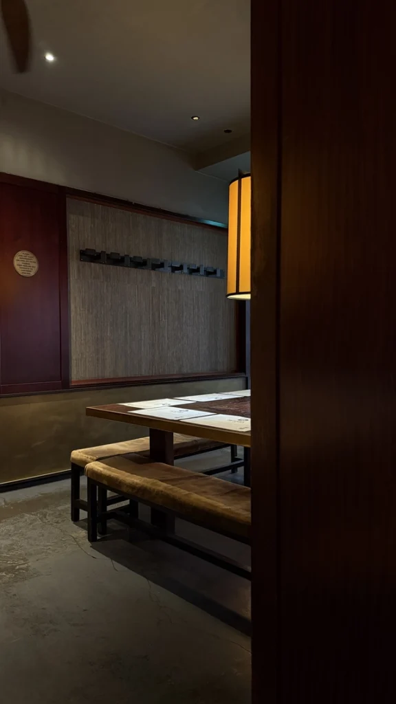 Interior of Busaba restaurant in London with warm lighting, large wooden sharing tables, and a cozy modern Thai atmosphere.