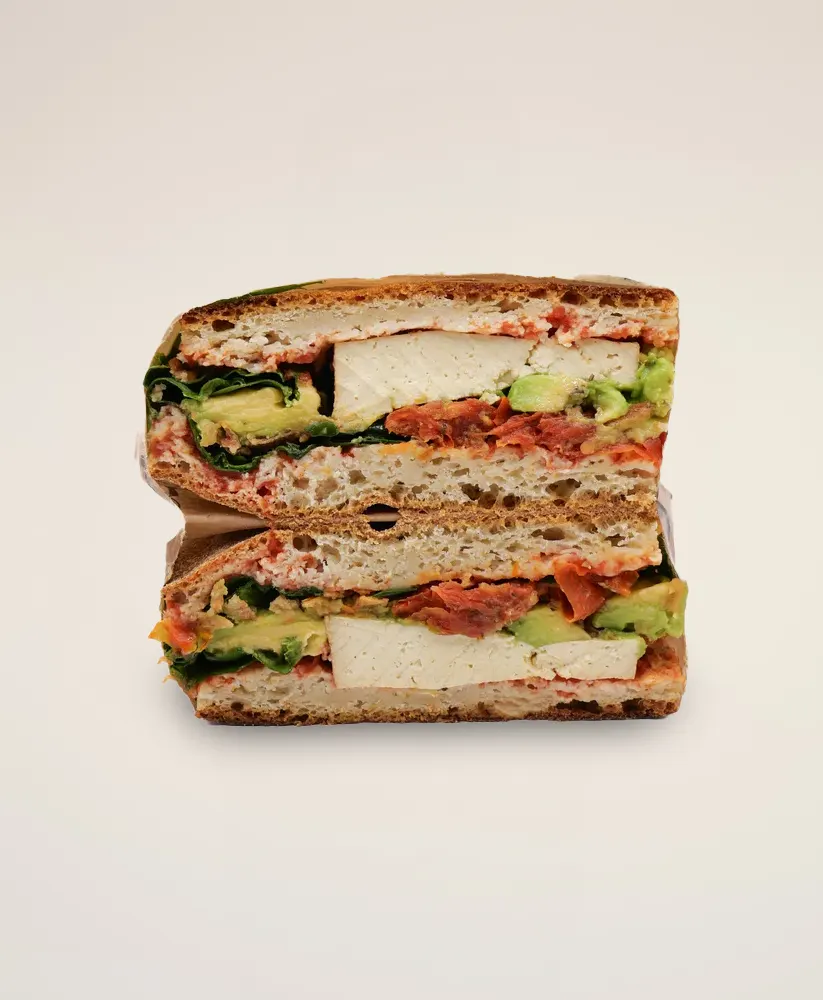Les Copains vegan sandwich with gluten-free bread, tofu, fresh vegetables, and plant-based filling.