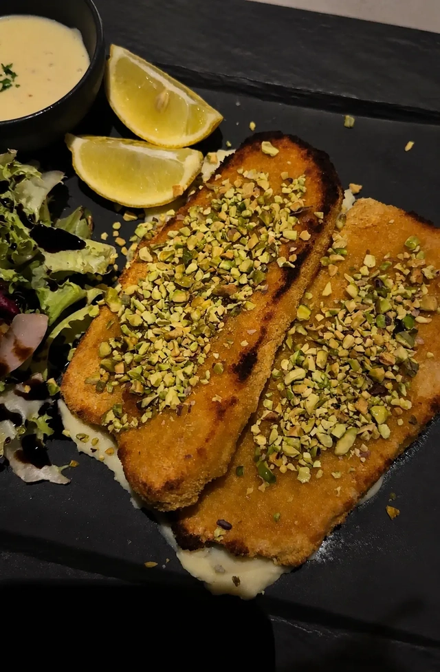 Vegan restaurants in Madrid: vegan pistachio-crusted salmon at Choose, served with lemon wedges, creamy sauce, and a small side salad.
