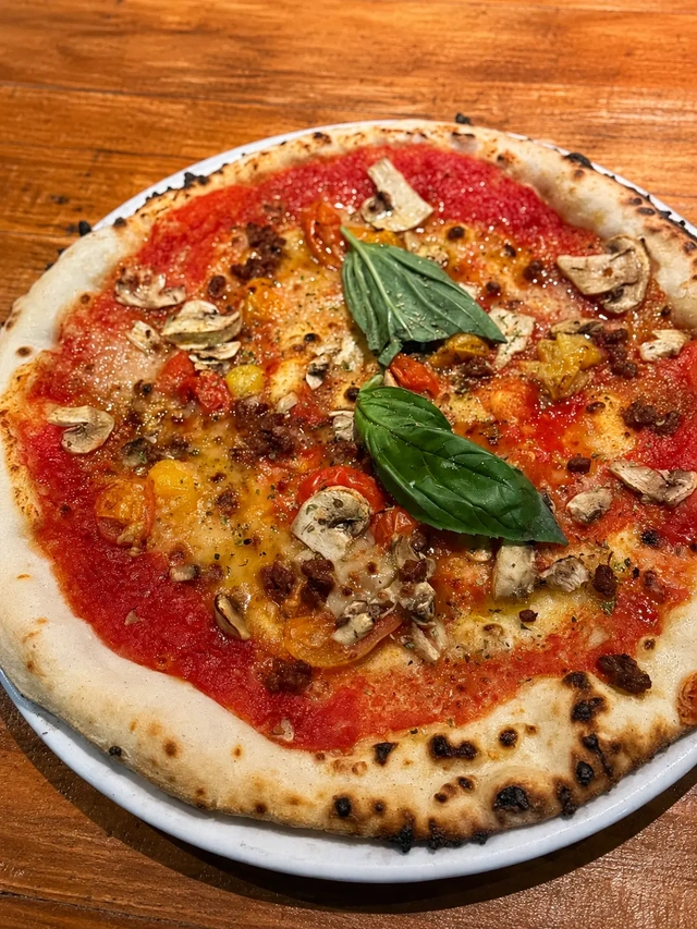 Vegan restaurants in Madrid, close-up of a gluten free vegan pizza at Grosso Napoletano with tomato sauce, basil, mushrooms, and a blistered crust.