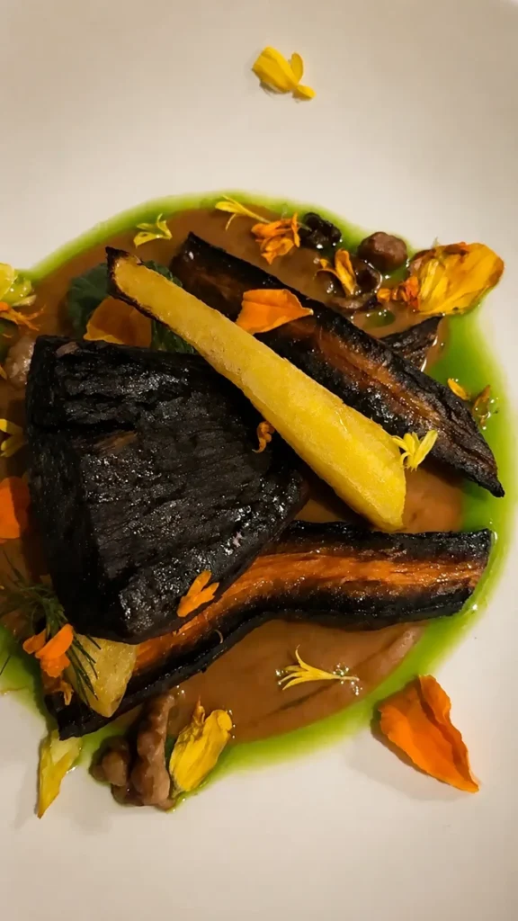 vegan restaurants in Madrid, colorful gourmet plant-based dish at Mudra with roasted vegetables, green sauce, and edible flowers.