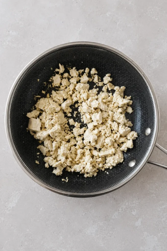 vegan tofu scramble crumbled tofu cooking in a nonstick pan
