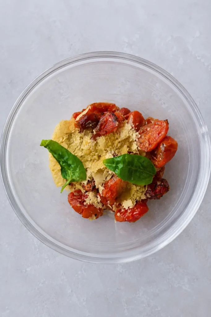 Vegan tomato pasta sauce ingredients with roasted cherry tomatoes, garlic, basil, and nutritional yeast before blending.