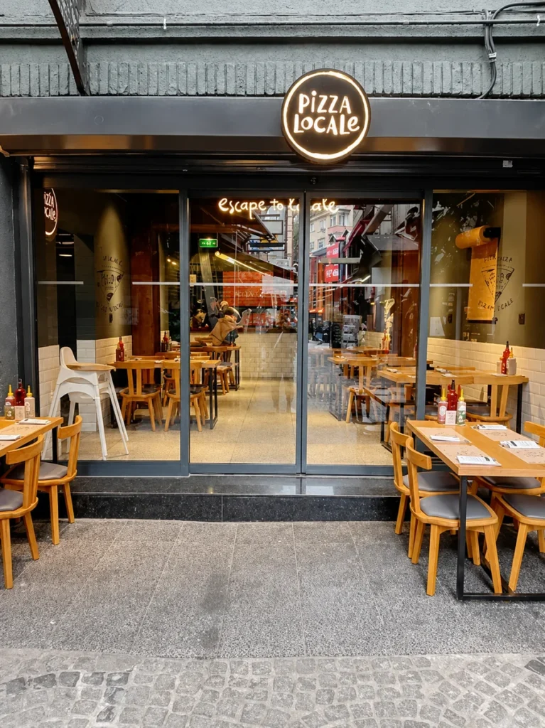 vegan restaurants in Istanbul, exterior of Pizza Locale with outdoor tables and a bright storefront in the city.