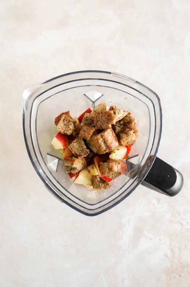 Vegan gazpacho ingredients added to a blender with soaked bread, fruit, vegetables, and seasoning before blending