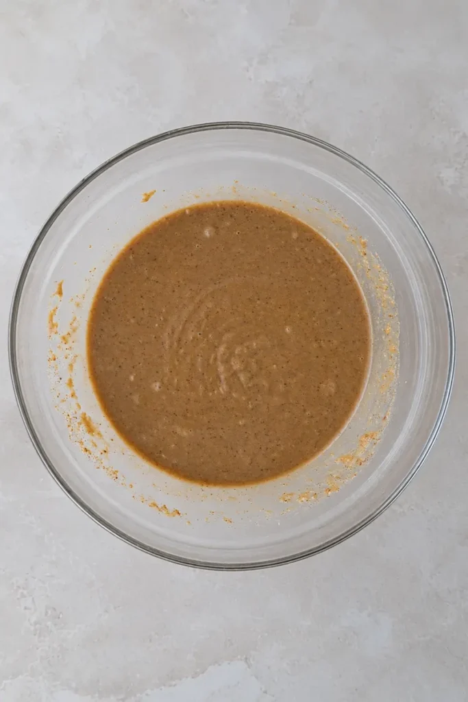 Apple sauce in a small bowl used as a vegan egg substitute for adding moisture and softness to cakes, muffins, and baked goods.