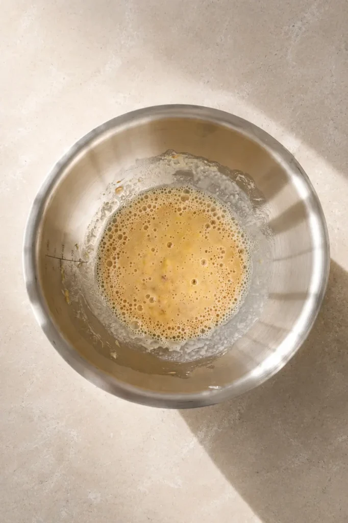 Mashed banana in a bowl used as a vegan egg substitute for adding moisture and binding in baking recipes.