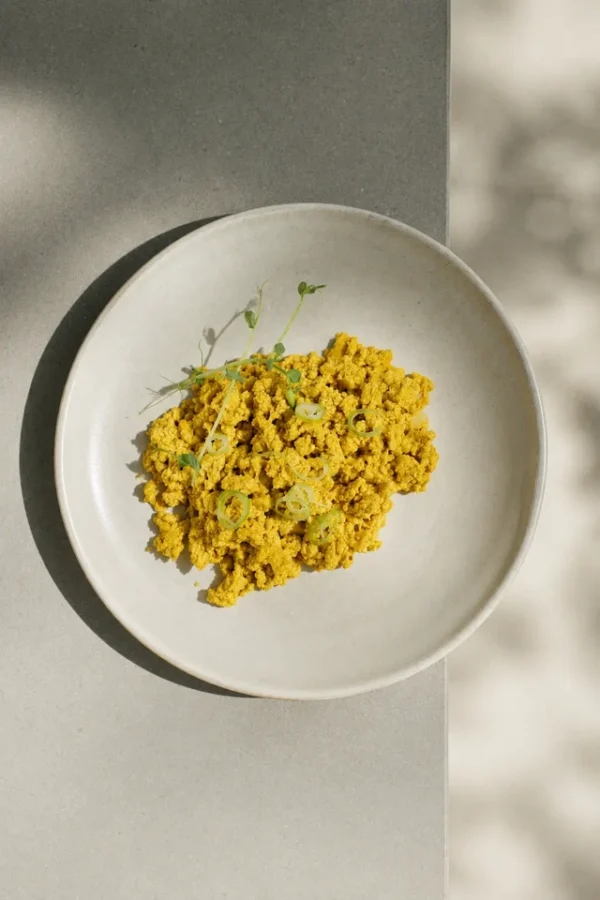 Vegan egg substitutes — silken tofu scrambled eggs with kala namak served in a white bowl