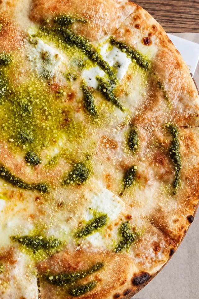 vegan restaurants in Istanbul, close-up of a white pizza with pesto, olive oil, and a soft golden crust at Pizza Locale.
