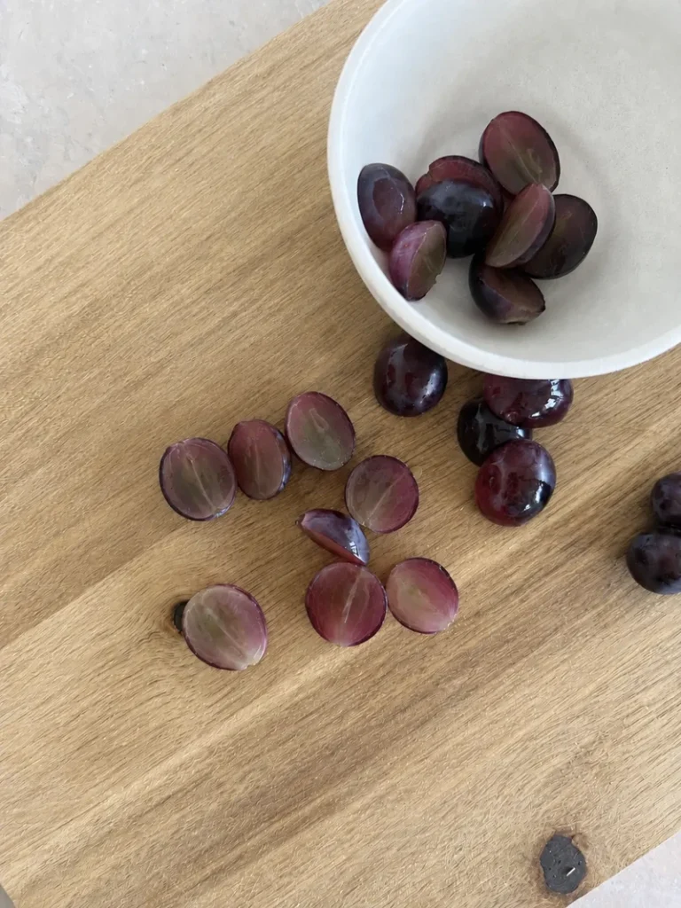 Vegan Waldorf Salad red grapes cut in half lengthwise on a wooden cutting board, ready to add to the salad.