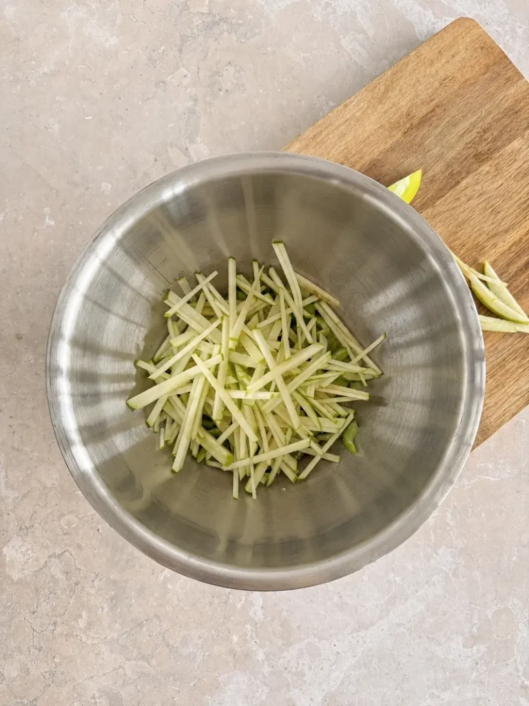Vegan Waldorf Salad apple and celery in a stainless steel mixing bowl, with julienned green apple and sliced celery ready to be mixed for the salad.