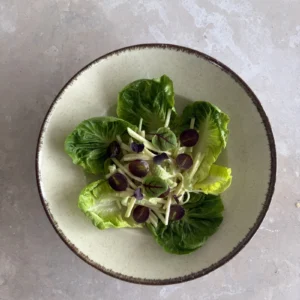 Vegan Waldorf Salad served over crisp lettuce leaves with creamy julienned apple and celery, halved red grapes, and delicate microgreens on a ceramic plate.
