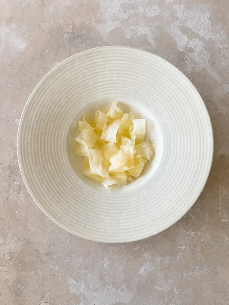 Cantaloupe ribbons arranged in a wide ceramic bowl during salad preparation