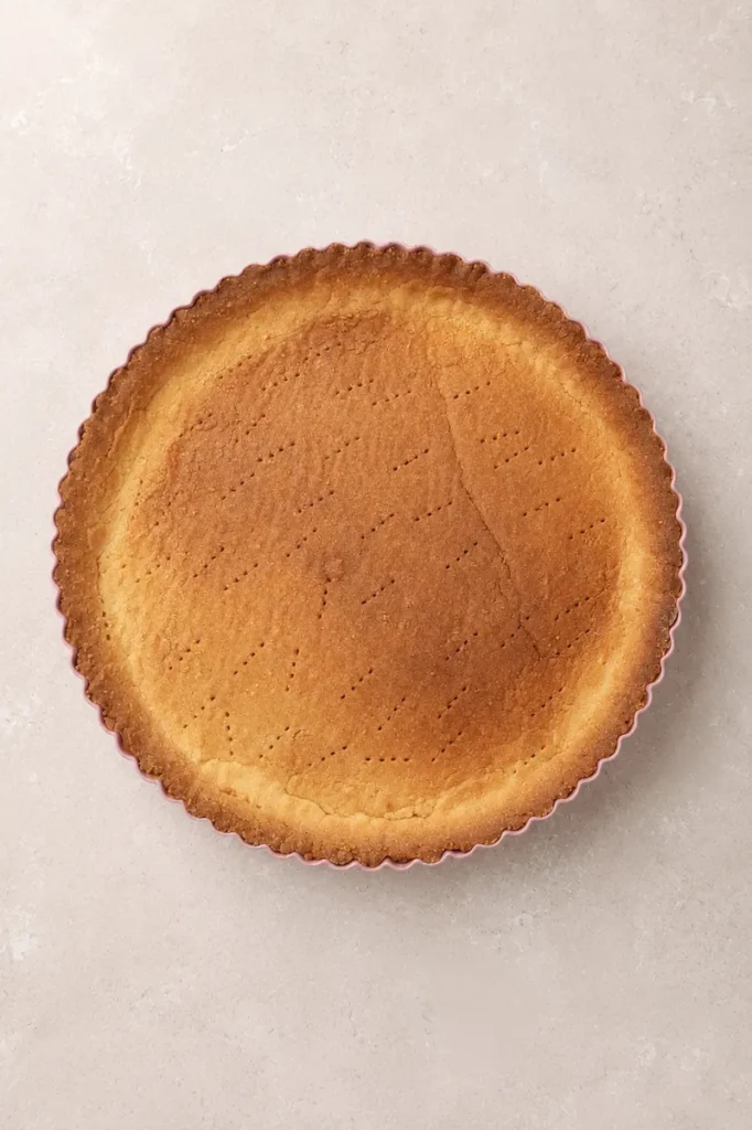 Baked gluten-free tart crust in a fluted tart pan, ready to be filled for a vegan lemon curd tart.