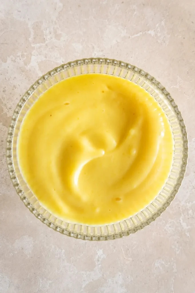 Smooth vegan lemon curd in a glass bowl, ready to fill the gluten-free tart crust.