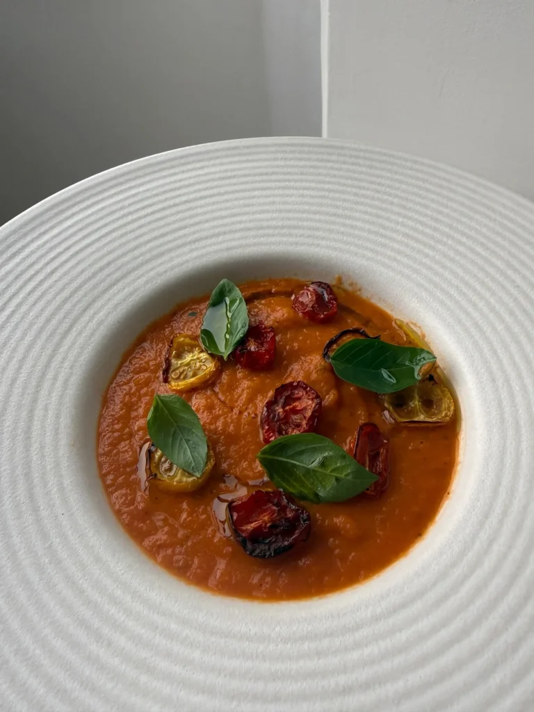 Creamy 3-ingredient tomato soup served with roasted cherry tomatoes, fresh basil leaves and a drizzle of olive oil.