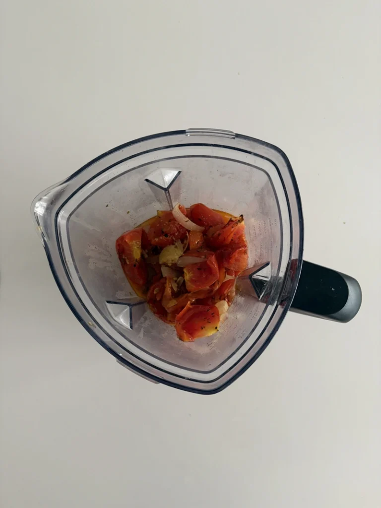 Roasted tomatoes, onion and garlic transferred to a blender, ready to be blended into a creamy 3-ingredient tomato soup.