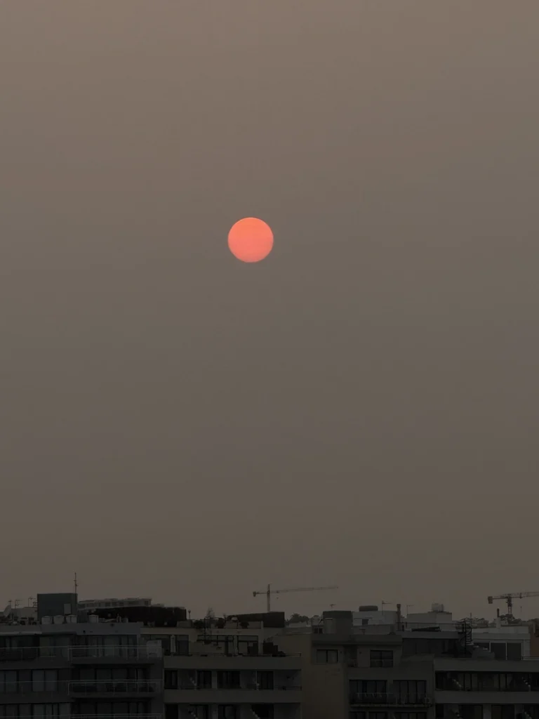 Warm red sun above a hazy city skyline, photographed as visual inspiration for the tomato soup recipe.