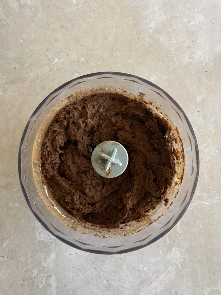 Thick chocolate batter blended in a food processor for high-protein vegan bean brownies.