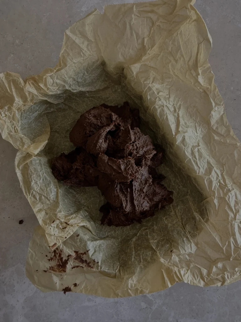Thick chocolate batter for high-protein vegan bean brownies transferred to a parchment-lined loaf pan.