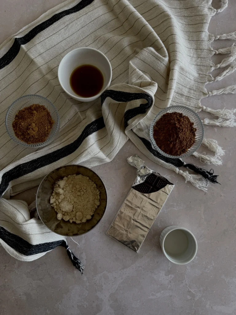 Ingredients for high-protein vegan bean brownies, including cocoa powder, almond flour, dark chocolate, maple syrup and coconut oil.