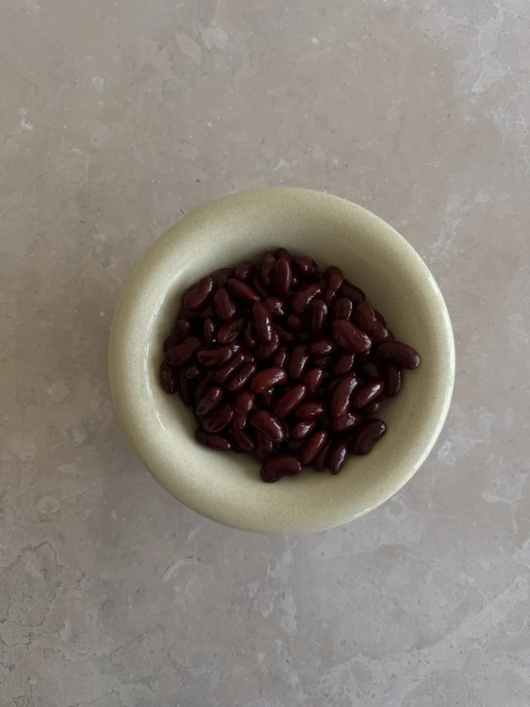 Red kidney beans arranged in a bowl at the centre of the frame, ready to make vegan gluten-free bean brownies.